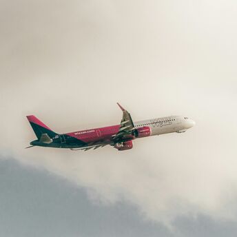 Wizz Air aircraft in flight against cloudy sky