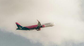 Wizz Air aircraft in flight against cloudy sky