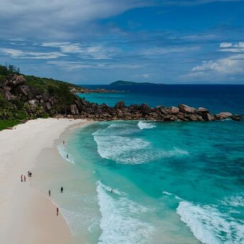 Aerial view of a beach on Seychelles, with turquoise waves and granite rock formations