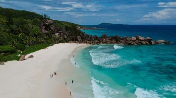Aerial view of a beach on Seychelles, with turquoise waves and granite rock formations