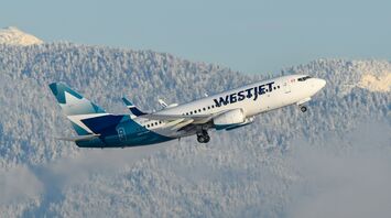 WestJet aircraft taking off with snowy mountains in the background