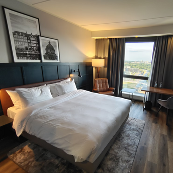 A hotel room featuring a large white bed positioned beside a window