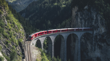 Train crossing a bridge surrounded by nature