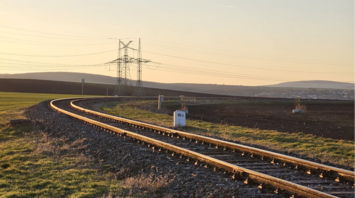 Railway track stretching through open fields at sunset in the Scottish Highlands