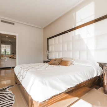 Bright hotel room with large bed, modern decor, and open bathroom view