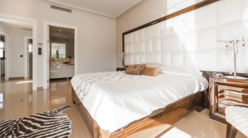 Bright hotel room with large bed, modern decor, and open bathroom view