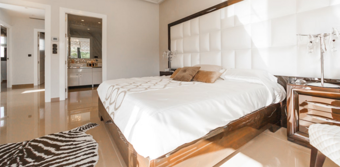 Bright hotel room with large bed, modern decor, and open bathroom view