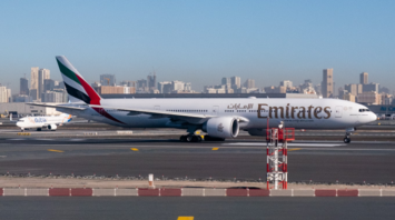 Emirates Boeing 777 taxiing at Dubai Airport with city skyline in background
