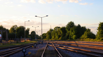 Railway tracks diverging under streetlights at sunset