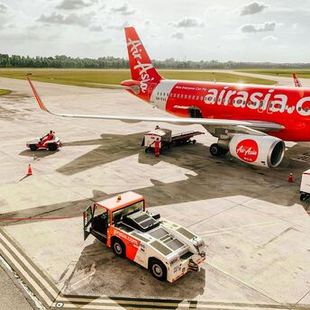 AirAsia aircraft being prepared on airport tarmac under cloudy sky