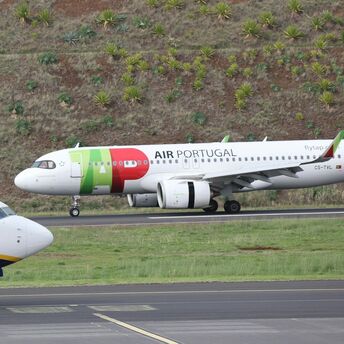 TAP Air Portugal aircraft taxiing on runway near hillside