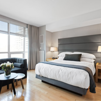 Modern hotel room with large windows, double bed, and a sofa