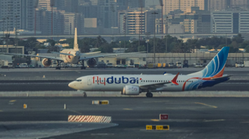 flydubai aircraft taxiing on runway with Dubai skyline in the background