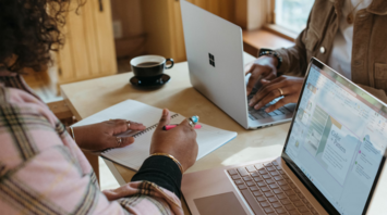 People working remotely with laptops and notes at a shared table