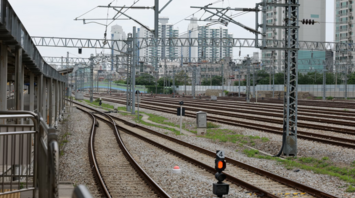 Multiple railway tracks and overhead power lines near an urban station
