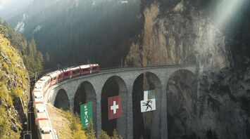Red scenic train crossing the Landwasser Viaduct in the Swiss Alps
