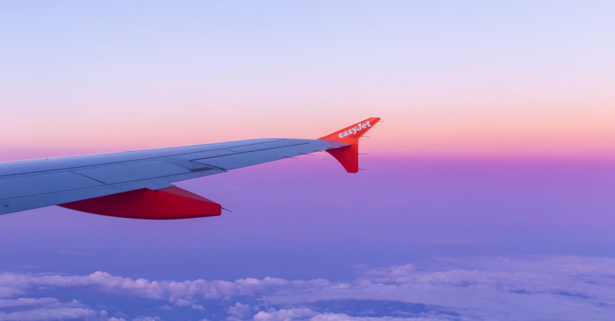 Red and white easyJet airplane wing against a blue sky during daytime