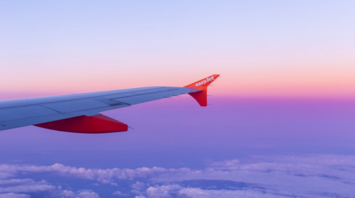 Red and white easyJet airplane wing against a blue sky during daytime