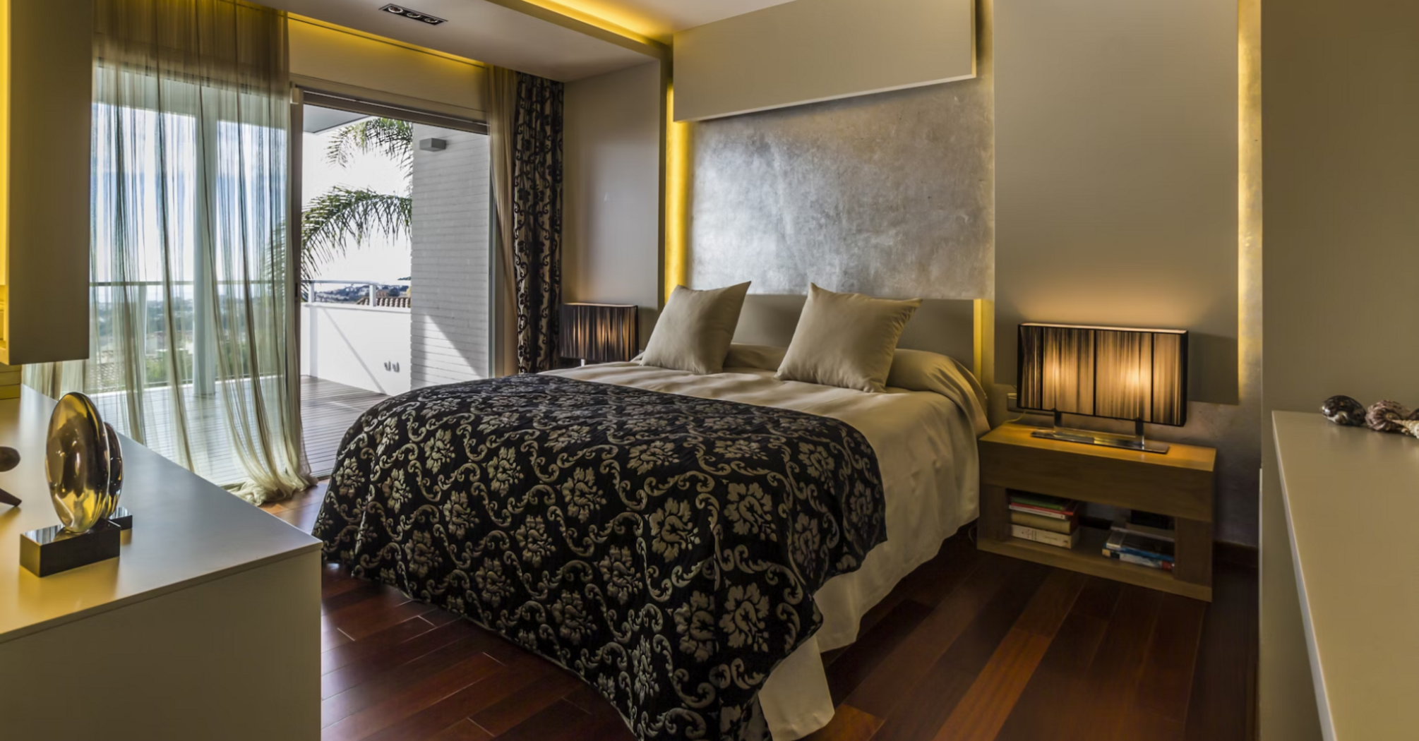 Modern hotel room with double bed, warm lighting, and balcony view