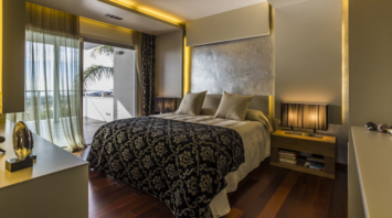 Modern hotel room with double bed, warm lighting, and balcony view