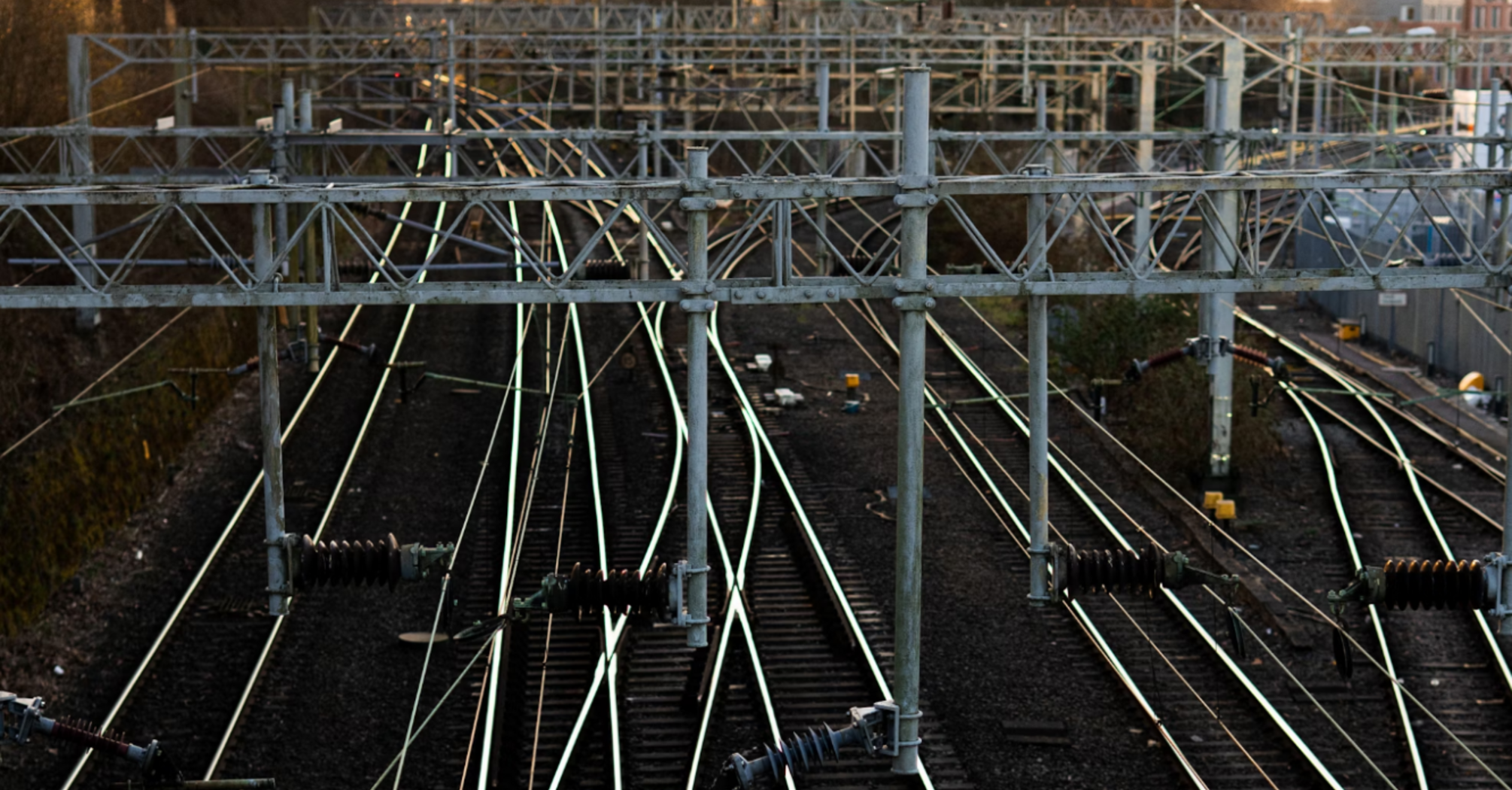Railway tracks with overhead electrical lines at sunset