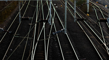 Railway tracks with overhead electrical lines at sunset