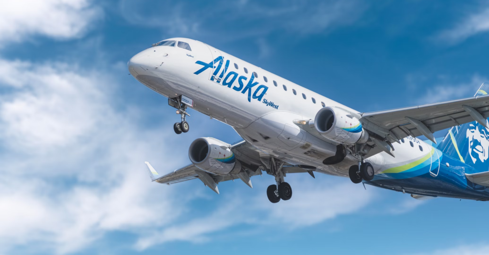 An Alaska Airlines plane flying under a clear blue sky