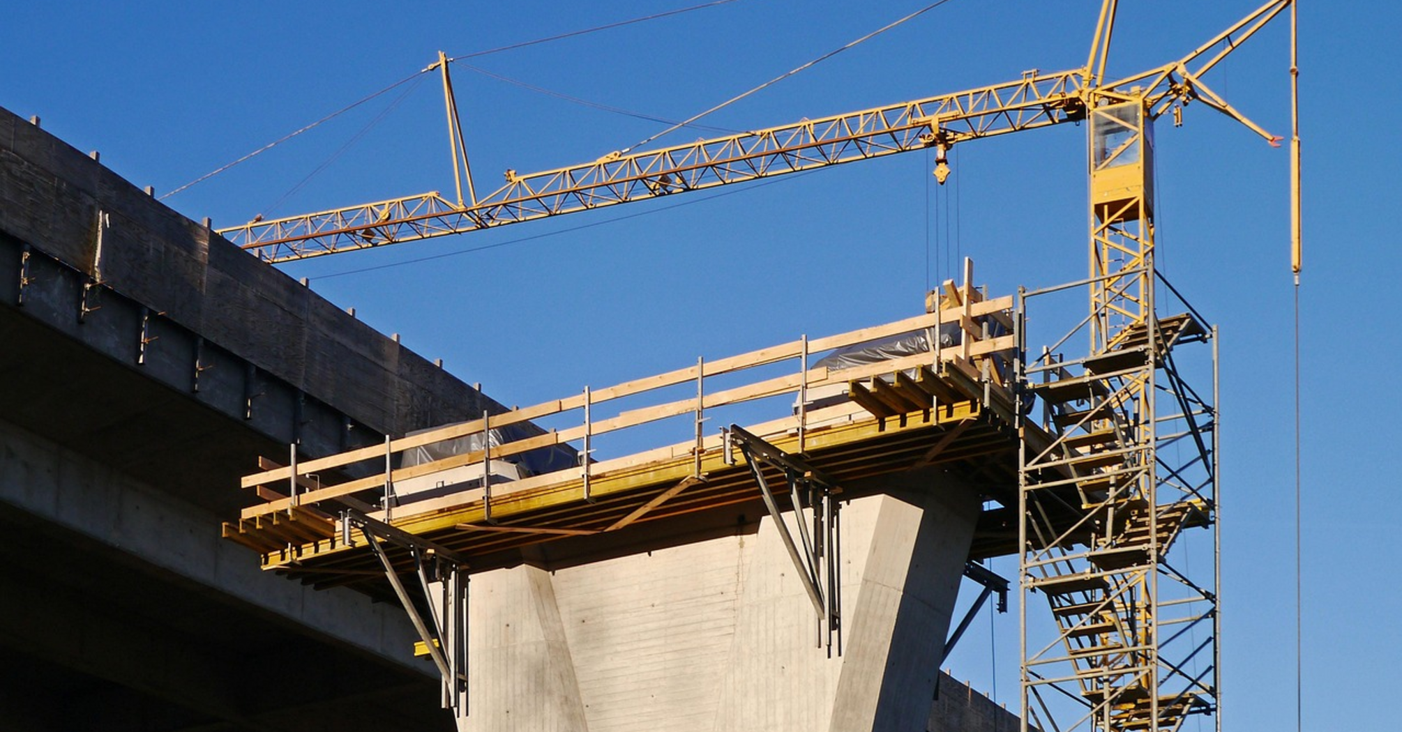 A large crane and scaffolding structure at a viaduct construction site under clear blue sky