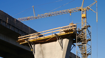 A large crane and scaffolding structure at a viaduct construction site under clear blue sky