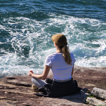 Woman meditating on a rocky shore near the ocean