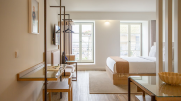 Modern hotel room with natural light, wood flooring, and minimalist furnishings