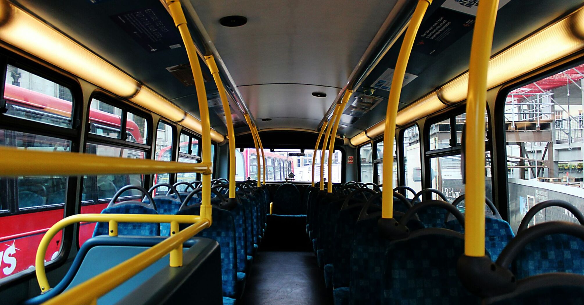 Interior of a public bus with empty seats and yellow handrails