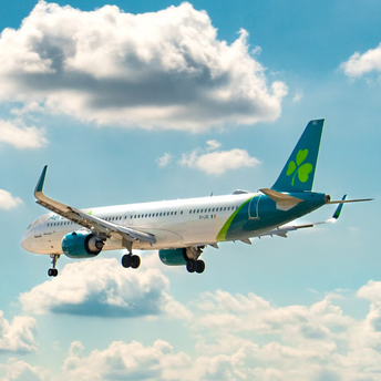 Commercial plane flying against a blue sky with clouds