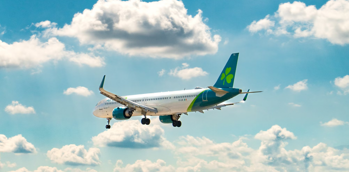 Commercial plane flying against a blue sky with clouds