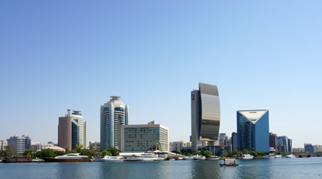 Modern buildings and yachts along Dubai Creek in Deira under a clear blue sky