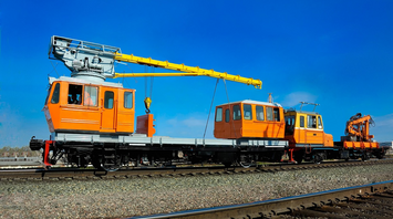 Rail maintenance vehicles on tracks under a clear blue sky
