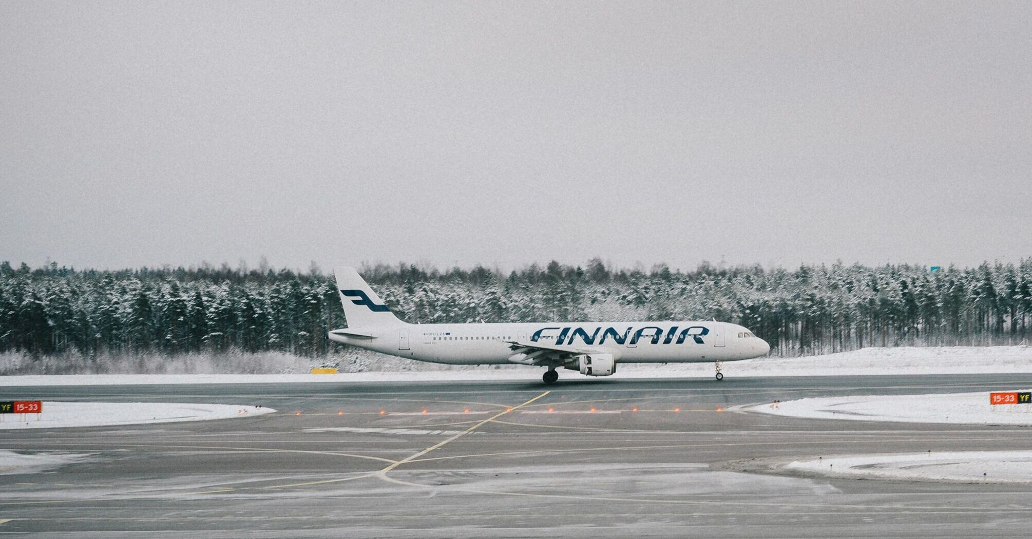 Finnair plane on snowy runway surrounded by forest