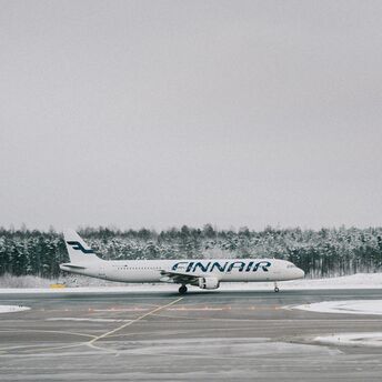Finnair plane on snowy runway surrounded by forest
