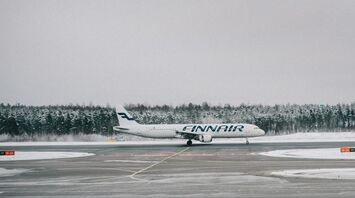 Finnair plane on snowy runway surrounded by forest