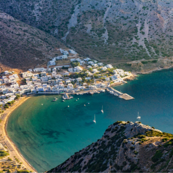 Aerial view of a coastal Greek village surrounded by mountains and a calm turquoise bay