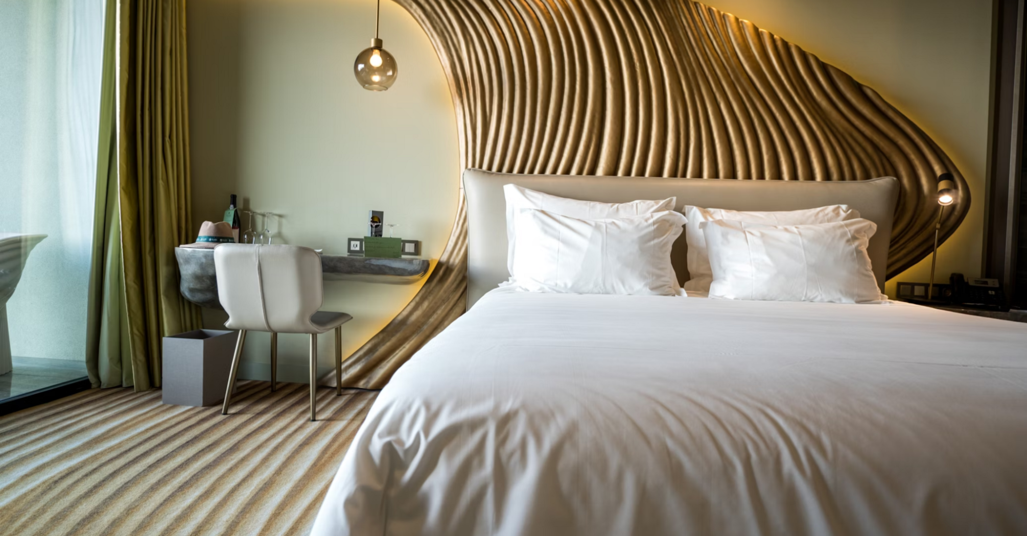 Stylish modern hotel room with sculpted wood paneling and white bedding