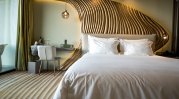Stylish modern hotel room with sculpted wood paneling and white bedding