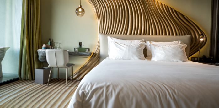Stylish modern hotel room with sculpted wood paneling and white bedding