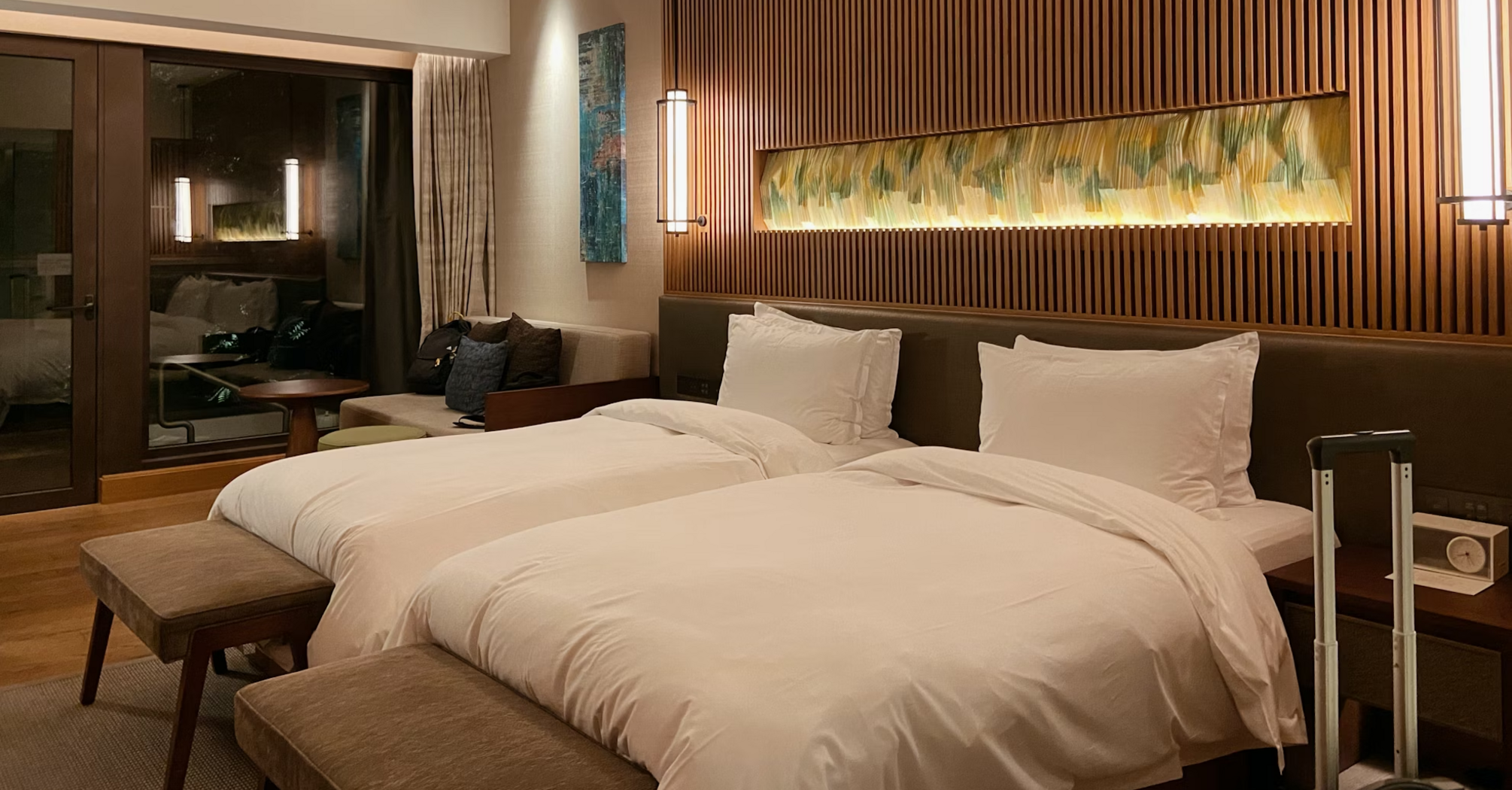Modern hotel room with twin beds, warm lighting, and wooden interior accents