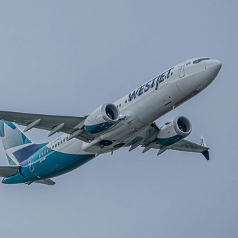 WestJet aircraft in flight against a grey sky