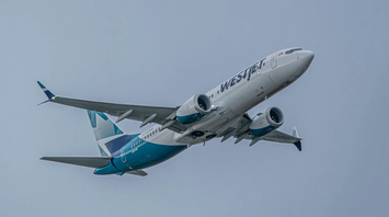 WestJet aircraft in flight against a grey sky