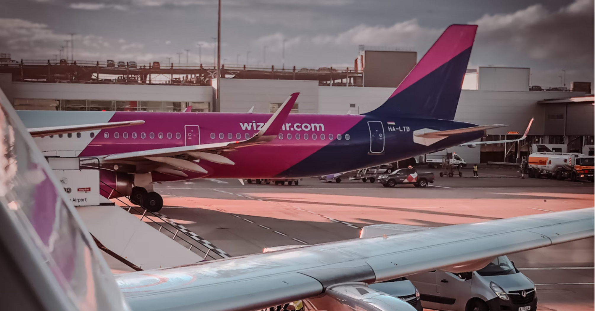 Wizz Air aircraft at airport gate with engine and tail in view