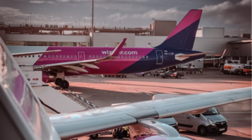 Wizz Air aircraft at airport gate with engine and tail in view