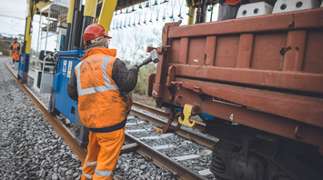Railway worker in safety gear near freight car during track maintenance