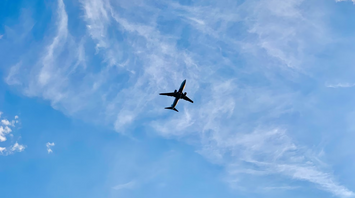 Plane flying in a clear blue sky with light clouds